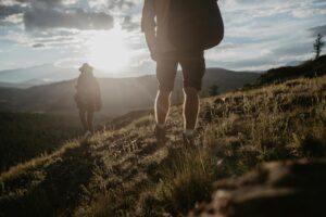 Two hikers explore the scenic Altai Mountains under the warm evening sun.