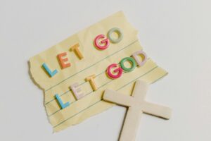 A note with the phrase 'Let Go, Let God' alongside a cross on a white background.