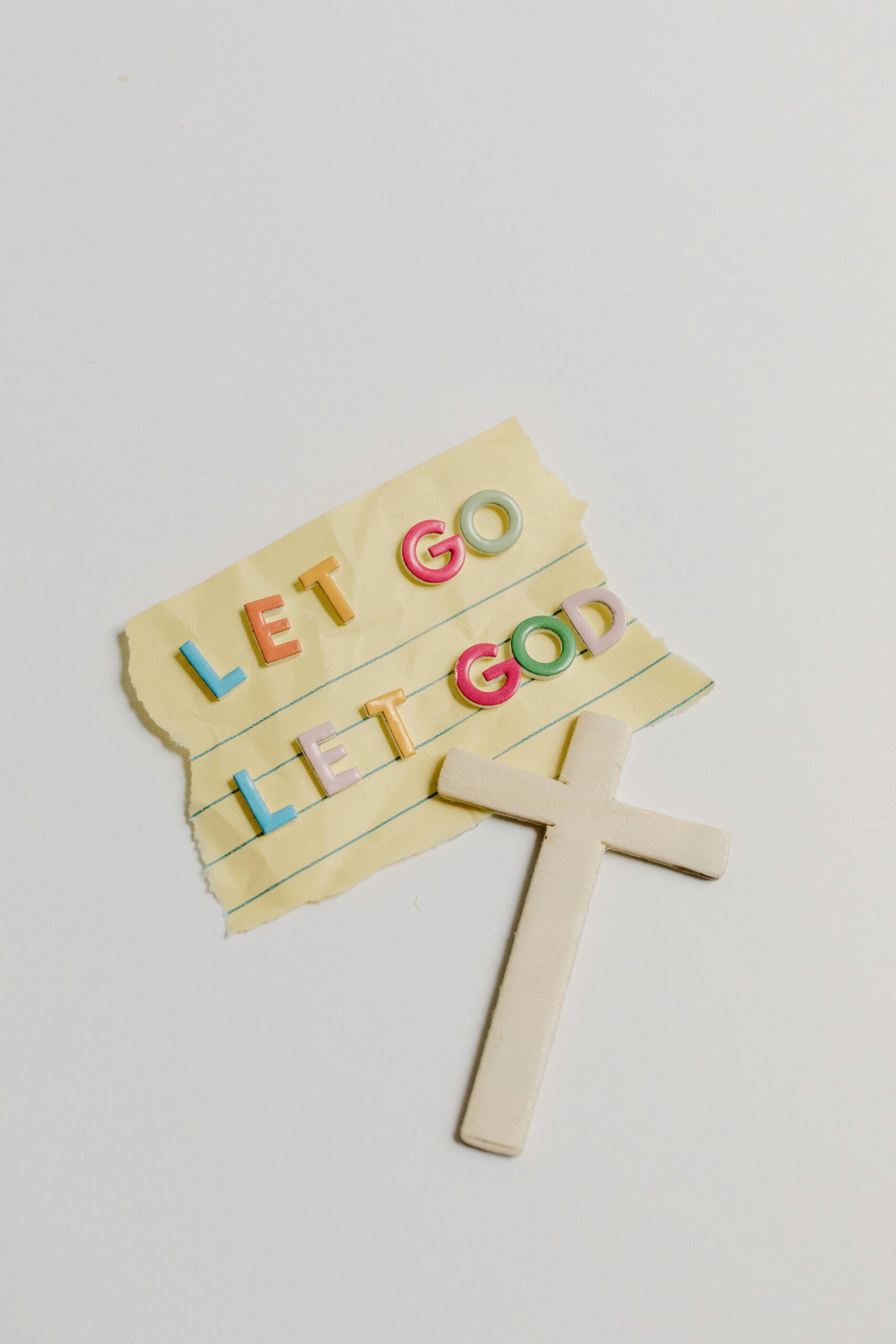 A note with the phrase 'Let Go, Let God' alongside a cross on a white background.