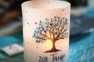 Beautiful decorative candle with tree design, illuminated for a baptism event with warm ambiance.