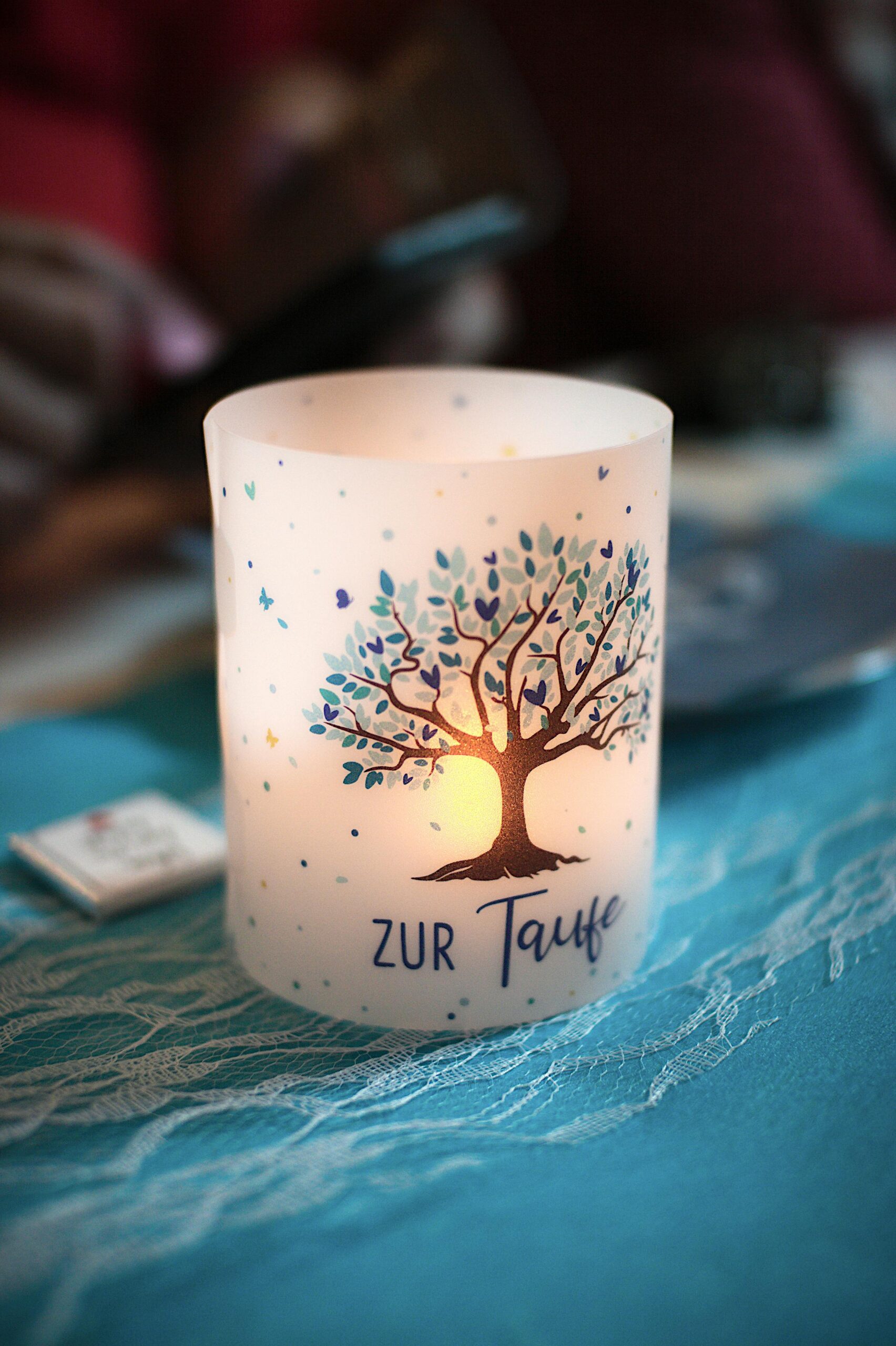 Beautiful decorative candle with tree design, illuminated for a baptism event with warm ambiance.