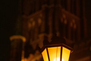 Warm glow of a street lamp with historic architecture in the background at night.